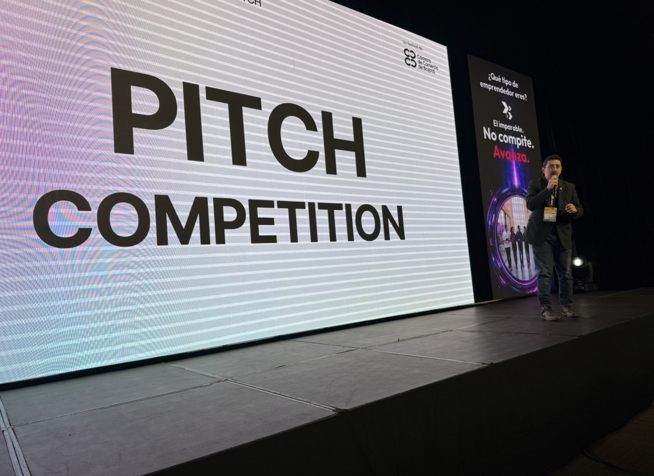 Julián Caicedo, CEO de Startti, habla en el escenario del Pitch Competition de GOFest 2026, con la pantalla gigante que muestra el texto PITCH COMPETITION a su lado.
